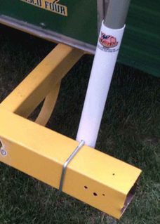White flagpole bumper mount on a travel trailers back bumper to hold a flagpole. The bumper is yellow in color.